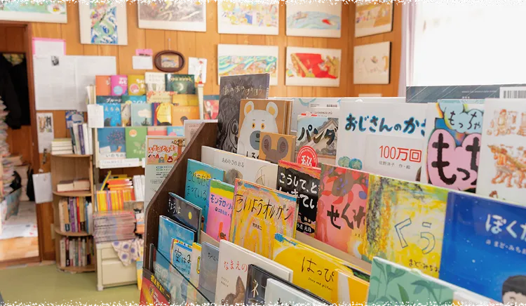 店内に並ぶ色とりどりの絵本と、木の温もりを感じる本棚
