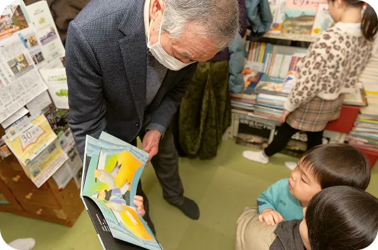 店主が子どもたちに絵本を手に取りながら紹介している様子